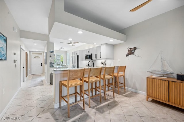 2370 Magnolia Ave Unit 6807, Naples, FL 34112 - kitchen featuring ceiling fan, a peninsula, a breakfast bar area, light tile patterned flooring, and recessed lighting