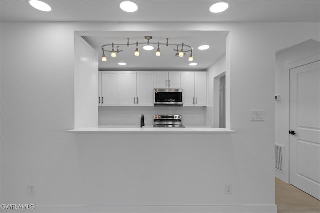 465 Donora Blvd, Fort Myers Beach, FL 33931 - kitchen featuring stainless steel appliances, white cabinetry, light countertops, tasteful backsplash, and a peninsula