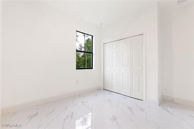 2803 E 13th St, Lehigh Acres, FL 33972 - unfurnished bedroom featuring light marble finish floors and a closet
