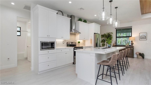 1030 22nd Ave NE, Naples, FL 34120 - kitchen with wall chimney exhaust hood, stainless steel appliances, a kitchen island with sink, recessed lighting, and light countertops