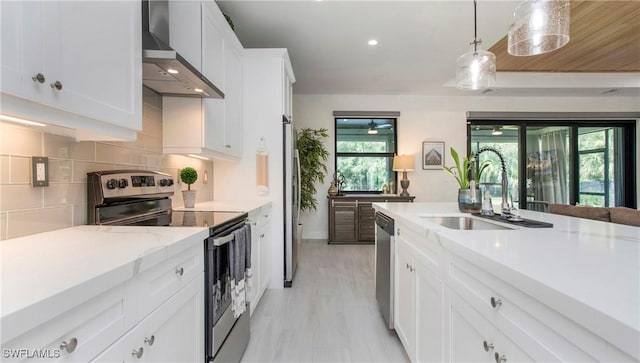 1030 22nd Ave NE, Naples, FL 34120 - kitchen featuring wall chimney exhaust hood, stainless steel appliances, white cabinetry, backsplash, and decorative light fixtures