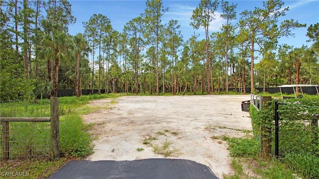 1030 22nd Ave NE, Naples, FL 34120 - view of dirt / gravel driveway with a gated entry and a view of trees
