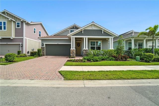 3387 Pilot Cir, Naples, FL 34120 - craftsman-style home featuring decorative driveway, a garage, stone siding, and a front lawn