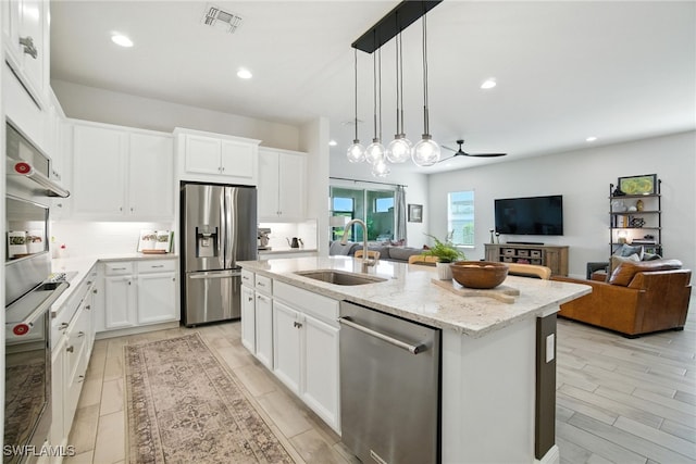 3387 Pilot Cir, Naples, FL 34120 - kitchen with appliances with stainless steel finishes, a ceiling fan, an island with sink, open floor plan, and light stone countertops