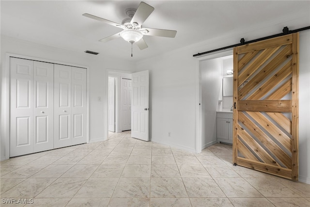 4811 Shady River Ln, Fort Myers, FL 33905 - unfurnished bedroom featuring a barn door, connected bathroom, a ceiling fan, and a closet