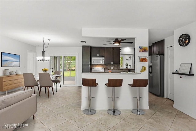 4811 Shady River Ln, Fort Myers, FL 33905 - kitchen with white appliances, a breakfast bar area, backsplash, a ceiling fan, and light tile patterned floors