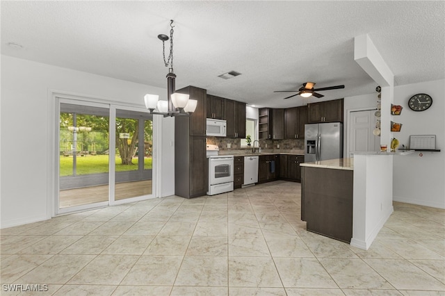 4811 Shady River Ln, Fort Myers, FL 33905 - kitchen with white appliances, dark brown cabinetry, light countertops, backsplash, and plenty of natural light