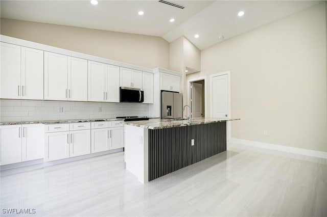 1117 SW Trafalgar Pkwy, Cape Coral, FL 33991 - kitchen with appliances with stainless steel finishes, light stone counters, a kitchen island with sink, decorative backsplash, and white cabinets