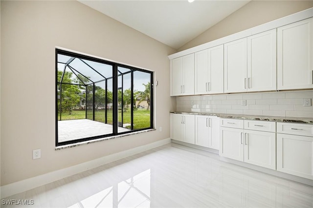 1117 SW Trafalgar Pkwy, Cape Coral, FL 33991 - kitchen with plenty of natural light, vaulted ceiling, stone counters, tasteful backsplash, and white cabinetry