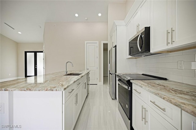 1328 SW 22nd Pl, Cape Coral, FL 33991 - kitchen with appliances with stainless steel finishes, white cabinets, tasteful backsplash, light stone countertops, and an island with sink
