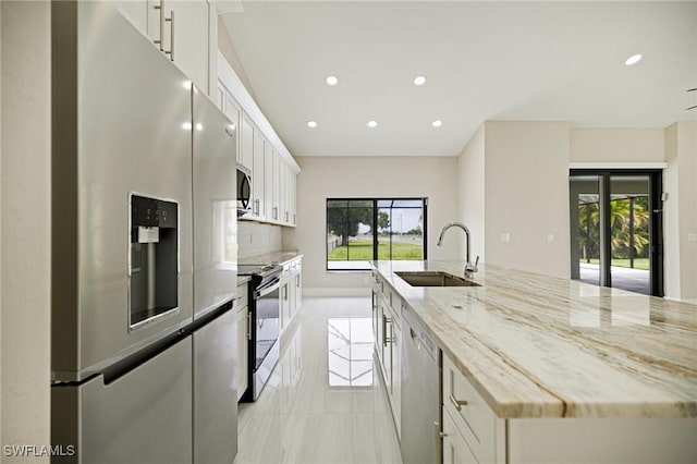 1328 SW 22nd Pl, Cape Coral, FL 33991 - kitchen with appliances with stainless steel finishes, recessed lighting, white cabinets, a spacious island, and light stone countertops