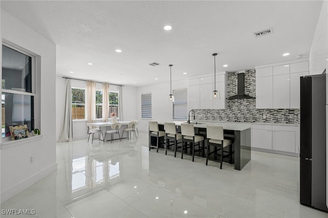 4868 Chisholm Park Trl, Saint Cloud, FL 34771 - kitchen featuring modern cabinets, wall chimney range hood, freestanding refrigerator, decorative backsplash, and white cabinets