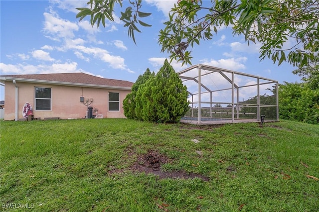 3213 22nd St SW, Lehigh Acres, FL 33976 - back of property with stucco siding, a yard, and glass enclosure