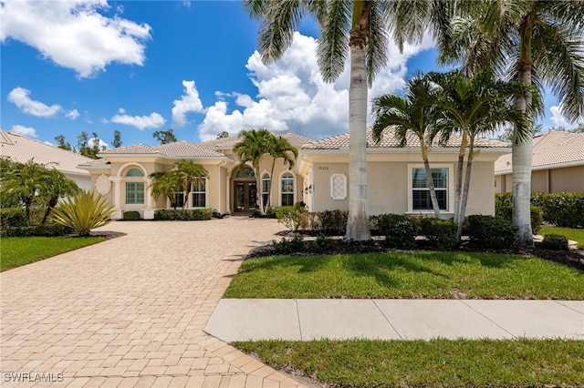 19332 La Serena Dr, Estero, FL 33967 - mediterranean / spanish-style home featuring decorative driveway, stucco siding, a front yard, and a tiled roof