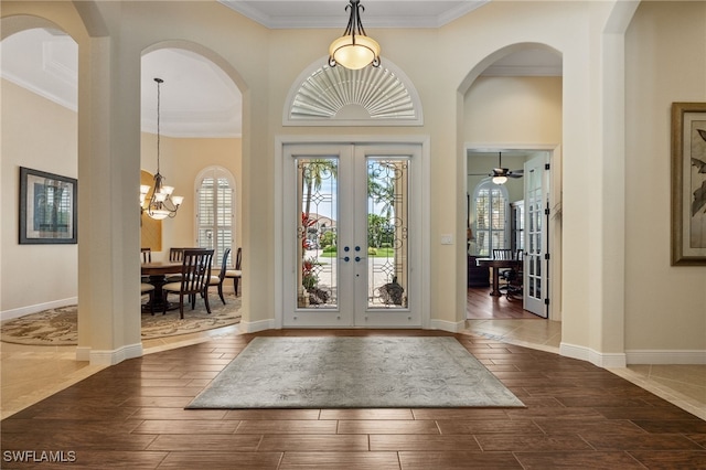 19332 La Serena Dr, Estero, FL 33967 - foyer entrance featuring french doors, crown molding, wood tiled floors, arched walkways, and a chandelier