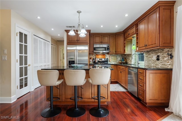 13660 Abbey Dr Unit 1, Fort Myers, FL 33919 - kitchen with stainless steel appliances, dark wood-type flooring, tasteful backsplash, a center island, and a breakfast bar