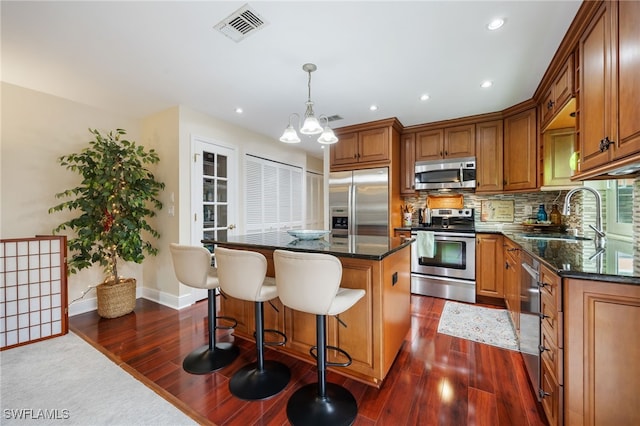 13660 Abbey Dr Unit 1, Fort Myers, FL 33919 - kitchen with stainless steel appliances, dark wood-style floors, a kitchen island, brown cabinetry, and tasteful backsplash
