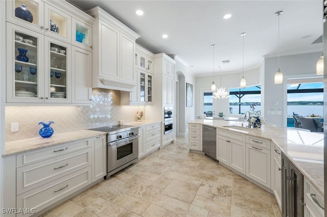 9380 Slate Ct, Naples, FL 34120 - kitchen featuring appliances with stainless steel finishes, backsplash, ornamental molding, white cabinetry, and decorative light fixtures