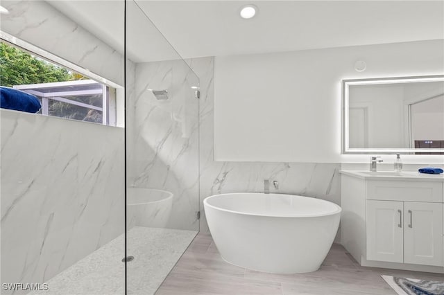 2050 Terrazzo Ln, Naples, FL 34104 - bathroom featuring a marble finish shower, vanity, a soaking tub, and wainscoting