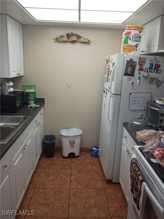 340 Easton Ct, Lehigh Acres, FL 33936 - kitchen featuring white range with gas cooktop, black microwave, white cabinets, dark countertops, and tile patterned floors