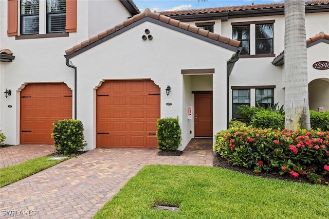 15140 Palmer Lake Cir Unit 201, Naples, FL 34109 - view of front of home with stucco siding, a tile roof, decorative driveway, and a garage