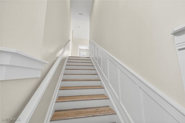 15140 Palmer Lake Cir Unit 201, Naples, FL 34109 - staircase featuring a decorative wall and a wainscoted wall