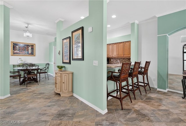 8014 Kilkenny Ct Unit G47, Naples, FL 34112 - kitchen featuring stone finish flooring, tasteful backsplash, arched walkways, a kitchen bar, and ornamental molding