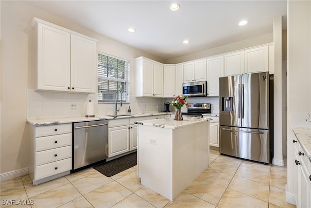 4780 Shinnecock Hills Ct Unit 102, Naples, FL 34112 - kitchen with appliances with stainless steel finishes, white cabinets, light stone counters, tasteful backsplash, and a kitchen island