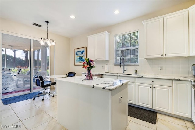 4780 Shinnecock Hills Ct Unit 102, Naples, FL 34112 - kitchen featuring a kitchen island, light tile patterned floors, light stone countertops, white cabinets, and recessed lighting