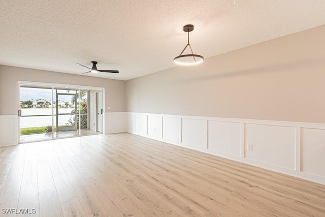 7718 Jewel Ln Unit 101, Naples, FL 34109 - unfurnished room with a textured ceiling, light wood finished floors, wainscoting, a decorative wall, and ceiling fan