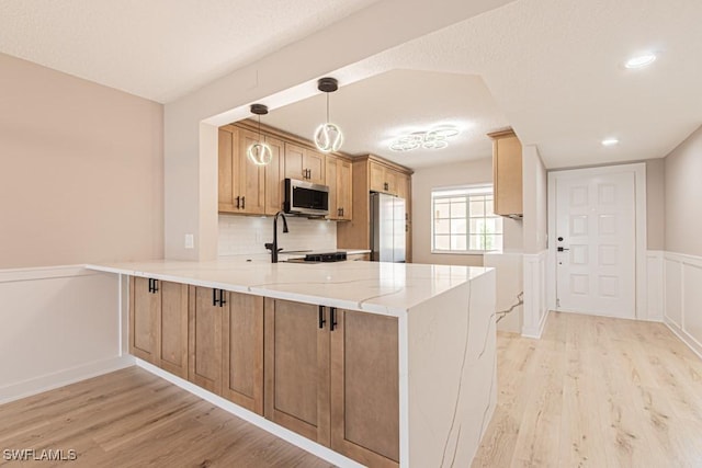 7718 Jewel Ln Unit 101, Naples, FL 34109 - kitchen with stainless steel microwave, a peninsula, light wood finished floors, freestanding refrigerator, and wainscoting