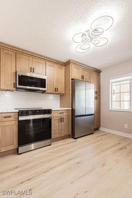 7718 Jewel Ln Unit 101, Naples, FL 34109 - kitchen with appliances with stainless steel finishes, light wood finished floors, a textured ceiling, light countertops, and tasteful backsplash