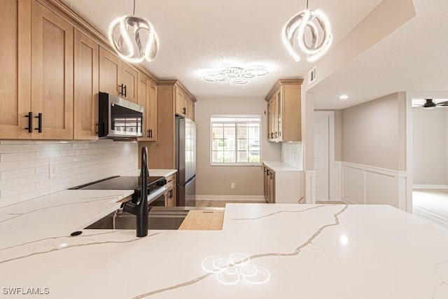 7718 Jewel Ln Unit 101, Naples, FL 34109 - kitchen featuring appliances with stainless steel finishes, light stone countertops, decorative backsplash, pendant lighting, and a textured ceiling