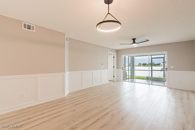 7718 Jewel Ln Unit 101, Naples, FL 34109 - empty room with a wainscoted wall, wood finished floors, a textured ceiling, a decorative wall, and ceiling fan