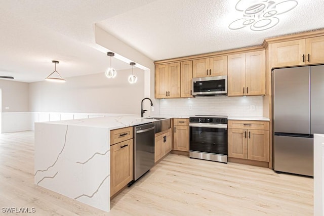 7718 Jewel Ln Unit 101, Naples, FL 34109 - kitchen with appliances with stainless steel finishes, a peninsula, light wood-type flooring, decorative backsplash, and pendant lighting