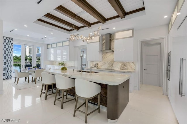 309 Neapolitan Way, Naples, FL 34103 - kitchen featuring wall chimney exhaust hood, modern cabinets, white cabinets, tasteful backsplash, and a breakfast bar