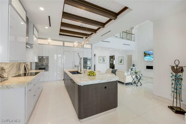 309 Neapolitan Way, Naples, FL 34103 - kitchen with modern cabinets, white cabinets, stainless steel double oven, black electric stovetop, and beamed ceiling