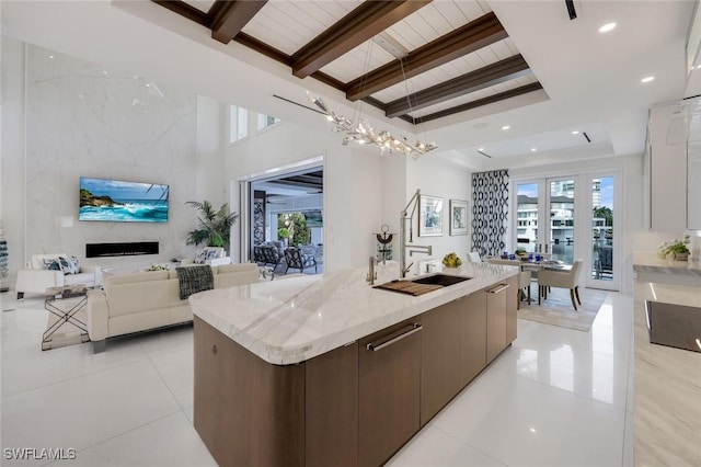 309 Neapolitan Way, Naples, FL 34103 - kitchen featuring modern cabinets, open floor plan, a large island, light tile patterned flooring, and a wood ceiling with exposed beams