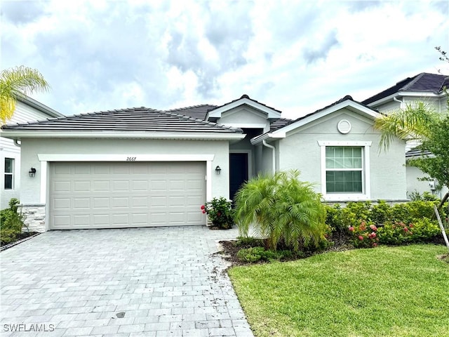 2667 Scarlet Way, Naples, FL 34120 - ranch-style house with decorative driveway, an attached garage, stucco siding, a front yard, and a tile roof