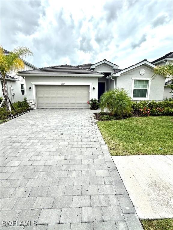 2667 Scarlet Way, Naples, FL 34120 - single story home featuring decorative driveway, an attached garage, a front lawn, and stucco siding