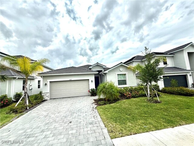 2667 Scarlet Way, Naples, FL 34120 - single story home with decorative driveway, a front yard, an attached garage, and stucco siding