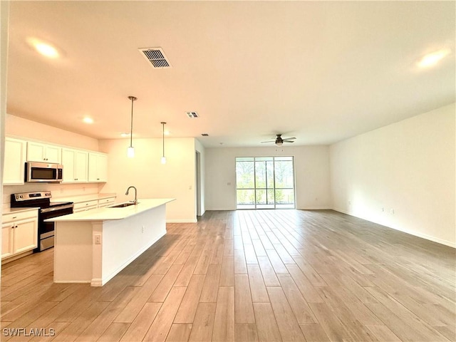 2667 Scarlet Way, Naples, FL 34120 - kitchen with stainless steel appliances, ceiling fan, light wood-style flooring, a kitchen island with sink, and open floor plan