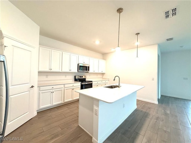 2667 Scarlet Way, Naples, FL 34120 - kitchen with appliances with stainless steel finishes, wood finished floors, white cabinets, a kitchen island with sink, and decorative light fixtures