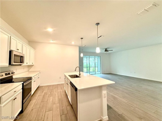 2667 Scarlet Way, Naples, FL 34120 - kitchen featuring appliances with stainless steel finishes, light wood finished floors, a center island with sink, a ceiling fan, and white cabinets