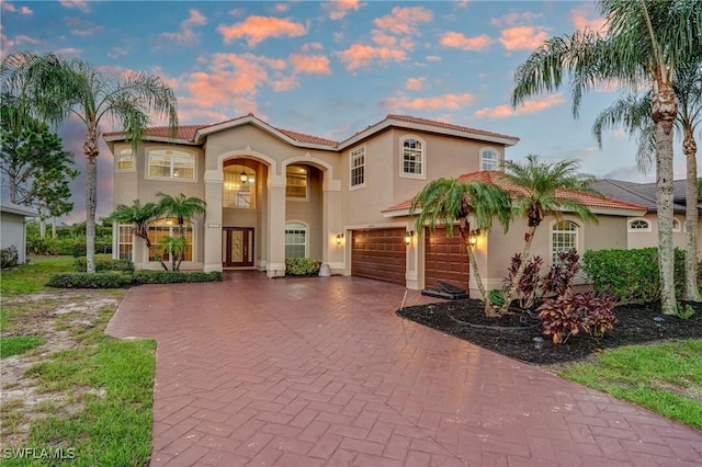 4582 Fairloop Run, Lehigh Acres, FL 33973 - mediterranean / spanish house with an attached garage, decorative driveway, stucco siding, and a tile roof