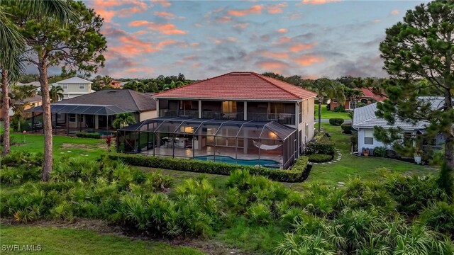 4582 Fairloop Run, Lehigh Acres, FL 33973 - back of house at dusk with an outdoor pool, a lawn, a patio, a lanai, and a tiled roof