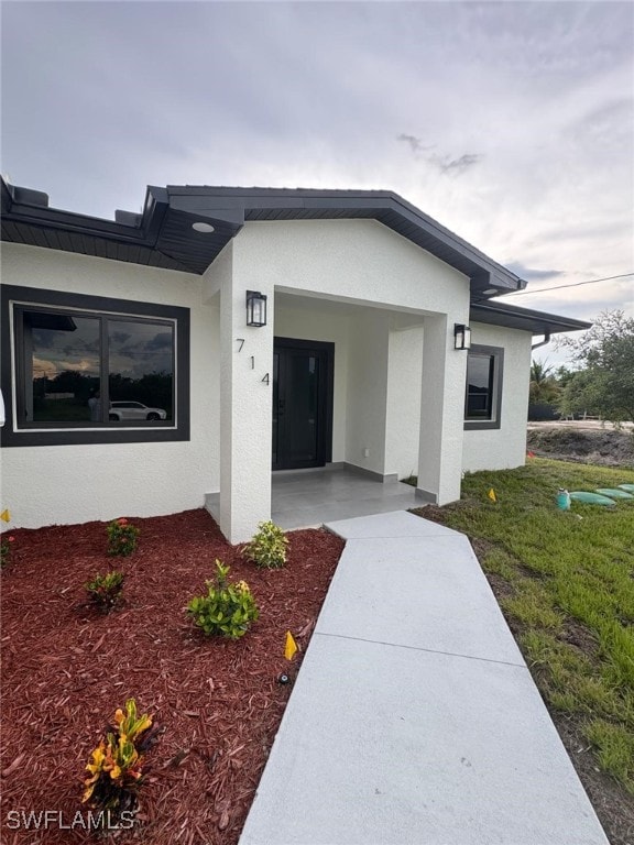 714 Euston Ave S, Lehigh Acres, FL 33974 - entrance to property featuring stucco siding and a yard