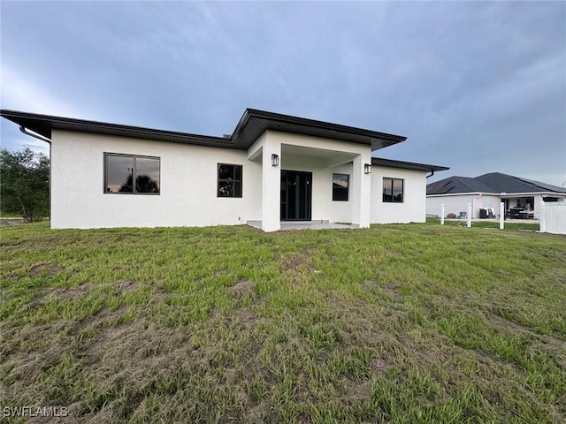 714 Euston Ave S, Lehigh Acres, FL 33974 - back of house featuring stucco siding and a yard