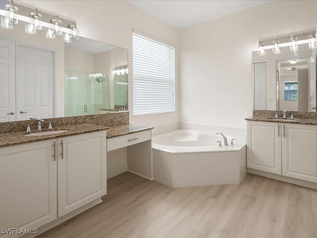 6491 Marbella Dr, Naples, FL 34105 - bathroom with wood finished floors, a stall shower, two vanities, and a bath
