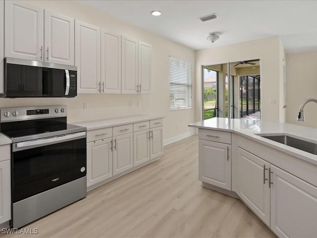 6491 Marbella Dr, Naples, FL 34105 - kitchen featuring stainless steel appliances, white cabinets, light countertops, light wood-style floors, and recessed lighting